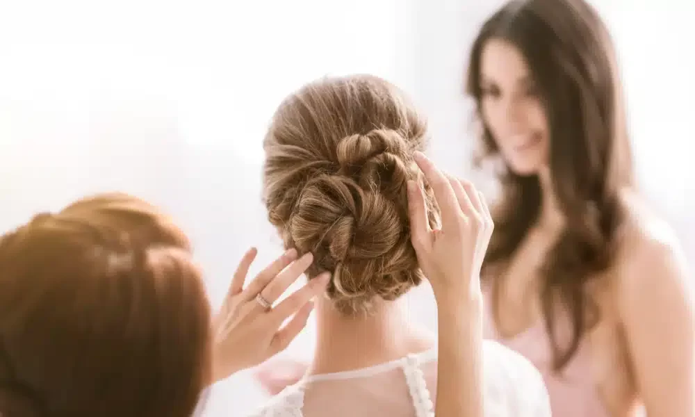 everything-must-be-perfect-delighted-cheerful-young-bridesmaids-sitting-white-bedroom-while-helping-bride-with-her-hairstyle-expressing-happiness